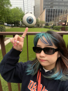 Photo of Patricia Tan pointing to eyeball sculpture